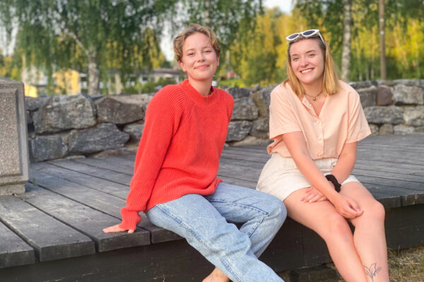Lotta Tuominen ja Aino Halinen istuvat rantapuiston puisella kävelysillalla.