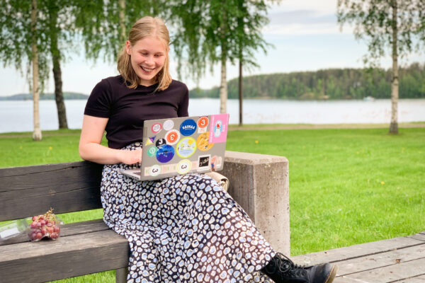 Vilma istuu puiston penkillä läppäri sylissään